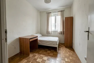 Petite chambre de moins de 9m2 avec lit simple et bureau dans un appartement à vendre